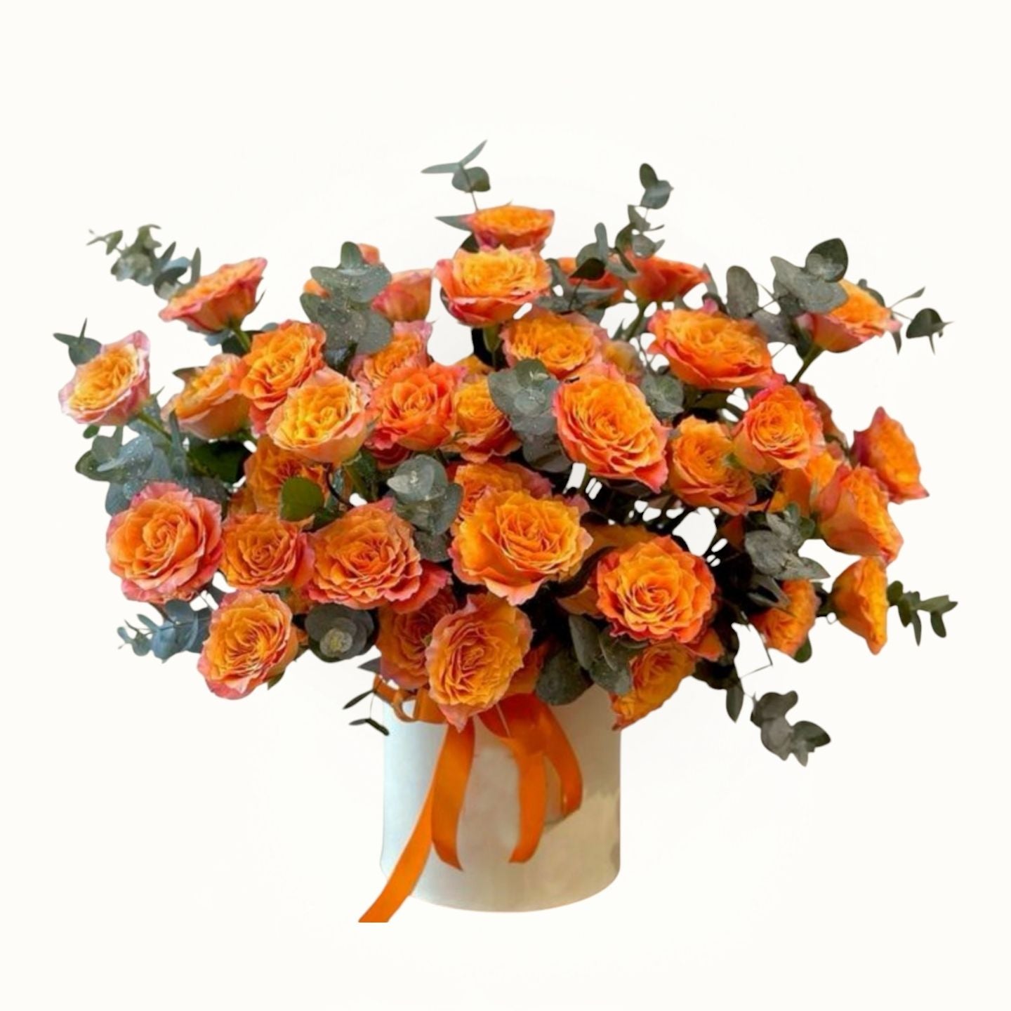 Bouquet of orange roses with greenery in a white container on a white background