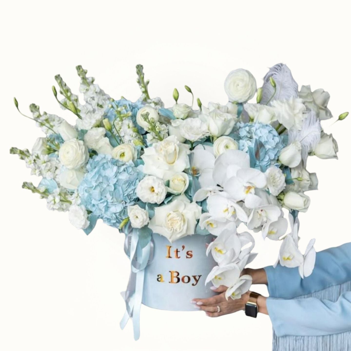 Floral arrangement in a box with 'It's a Boy' text, held by a person wearing a blue sweater.