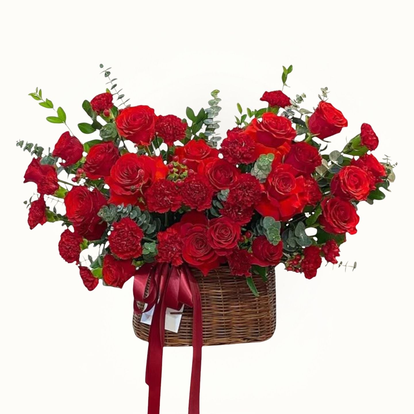 Bouquet of red roses in a basket with greenery on a white background