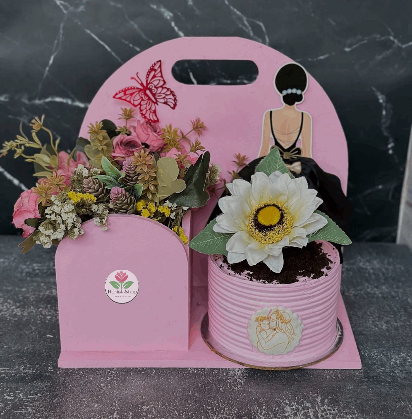 Pink decorative stand with floral arrangements on a dark marble surface