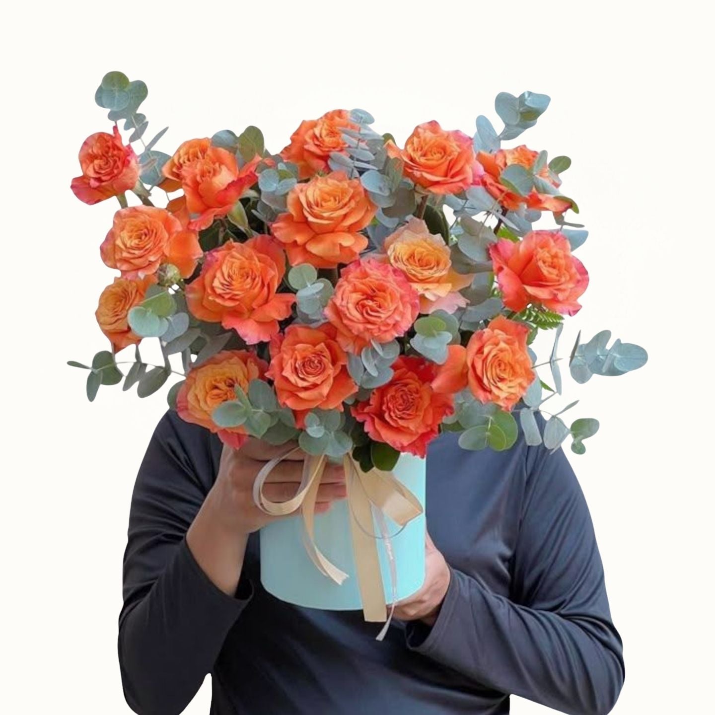 Bouquet of orange and pink roses with greenery held by a person against a white background