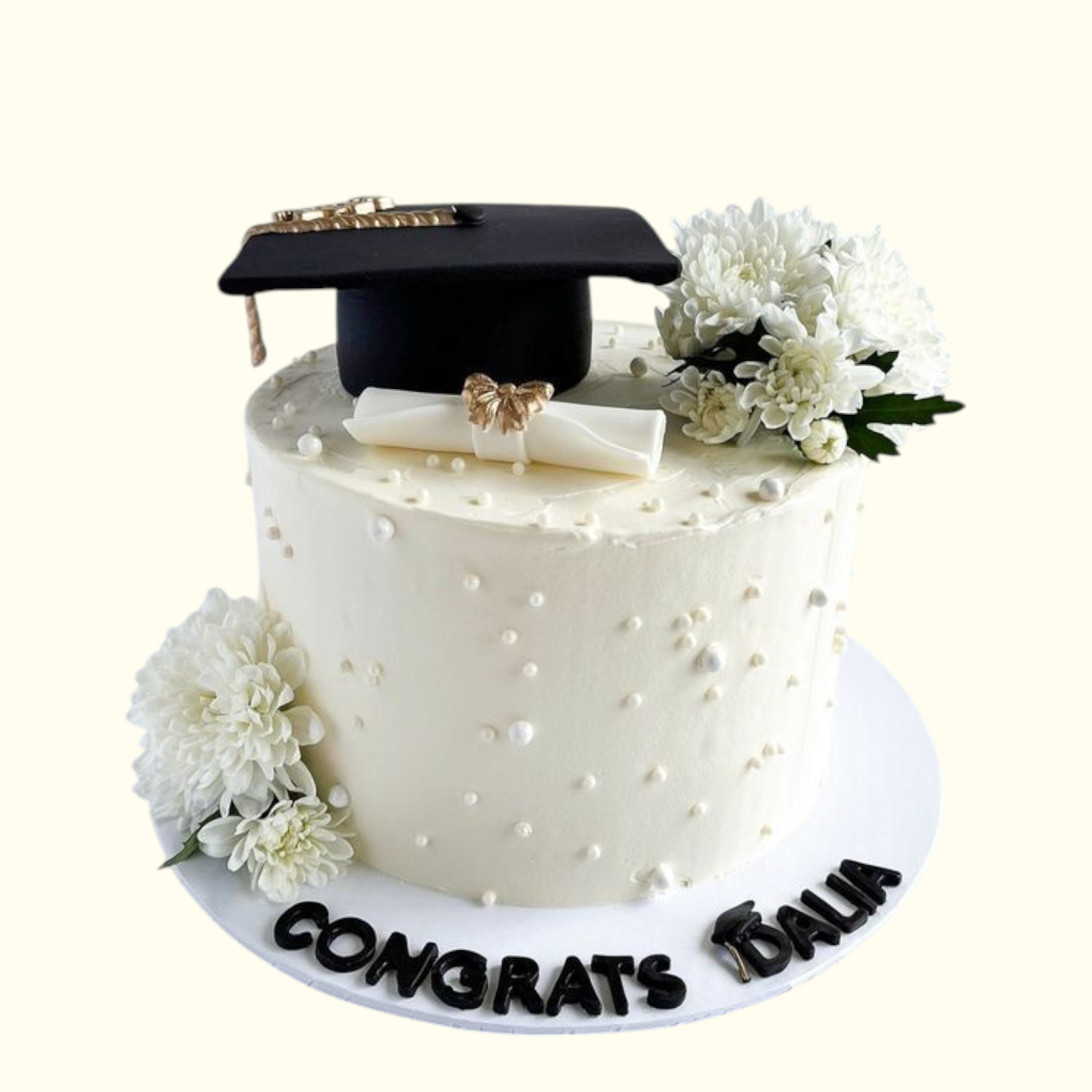 Graduation-themed cake with a black cap, white flowers, and 'CONGRATS ISABELLA' text on a white background