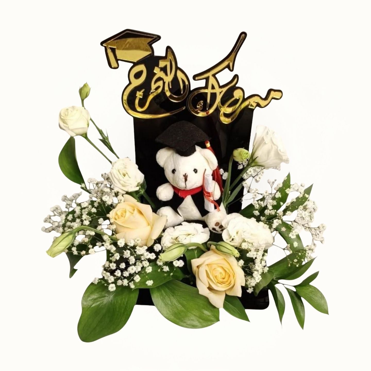Graduation-themed arrangement with a teddy bear, flowers, and a cap on a white background