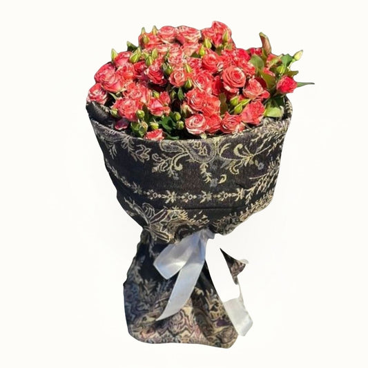 Bouquet of pink flowers wrapped in decorative paper with a white ribbon 