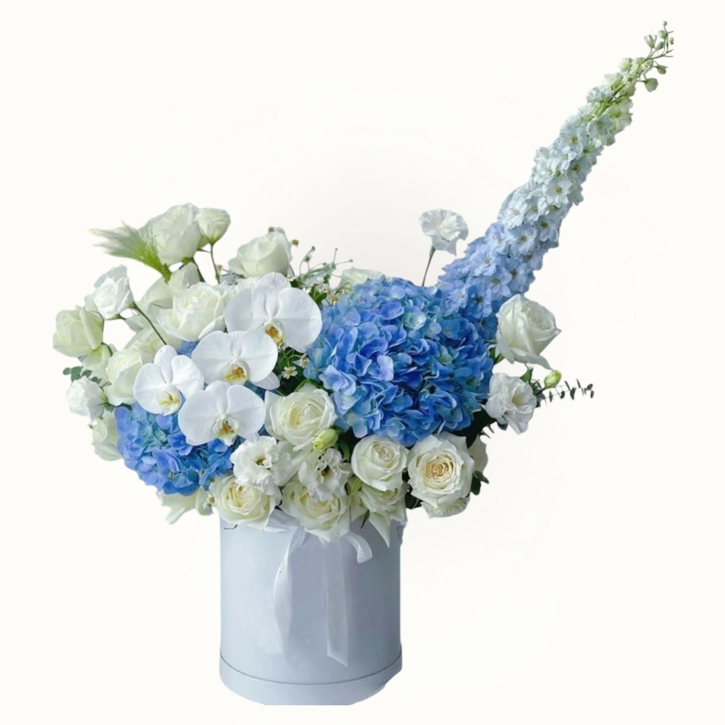 Floral arrangement with blue and white flowers in a white box on a white background