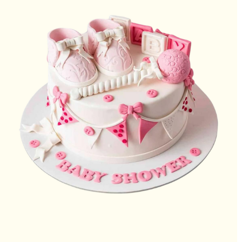 Baby shower cake with pink baby shoes, rattle, and 'Baby Shower' text on a white background