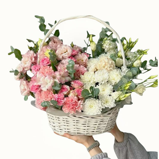 Basket of pink and white flowers held by a person on a white background