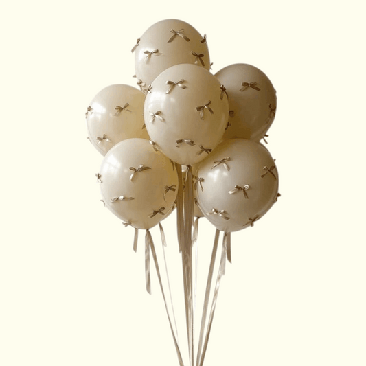 Set of cream-colored balloons with gold ribbons on a white background