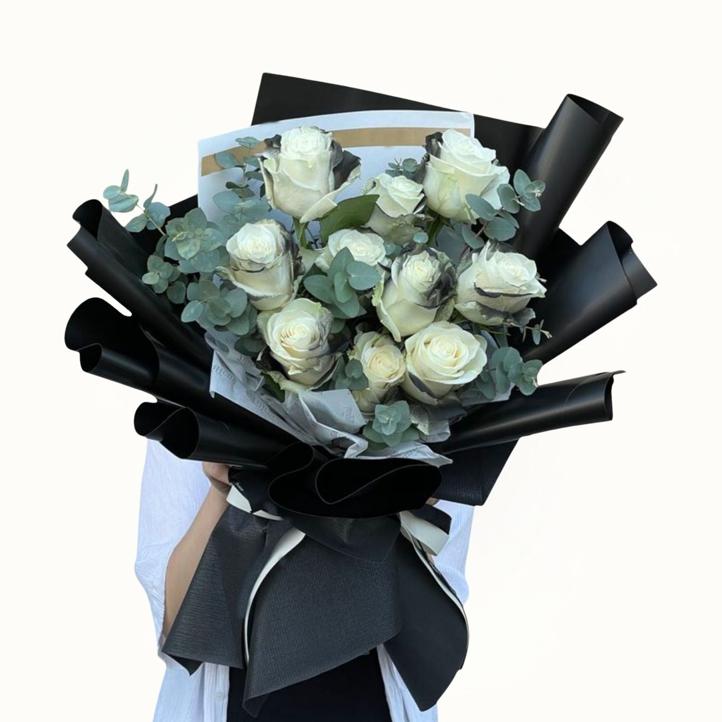 Bouquet of white roses wrapped in black paper with a black ribbon on a white background