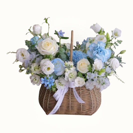 Floral arrangement in a woven basket with white, blue, and green flowers on a white background