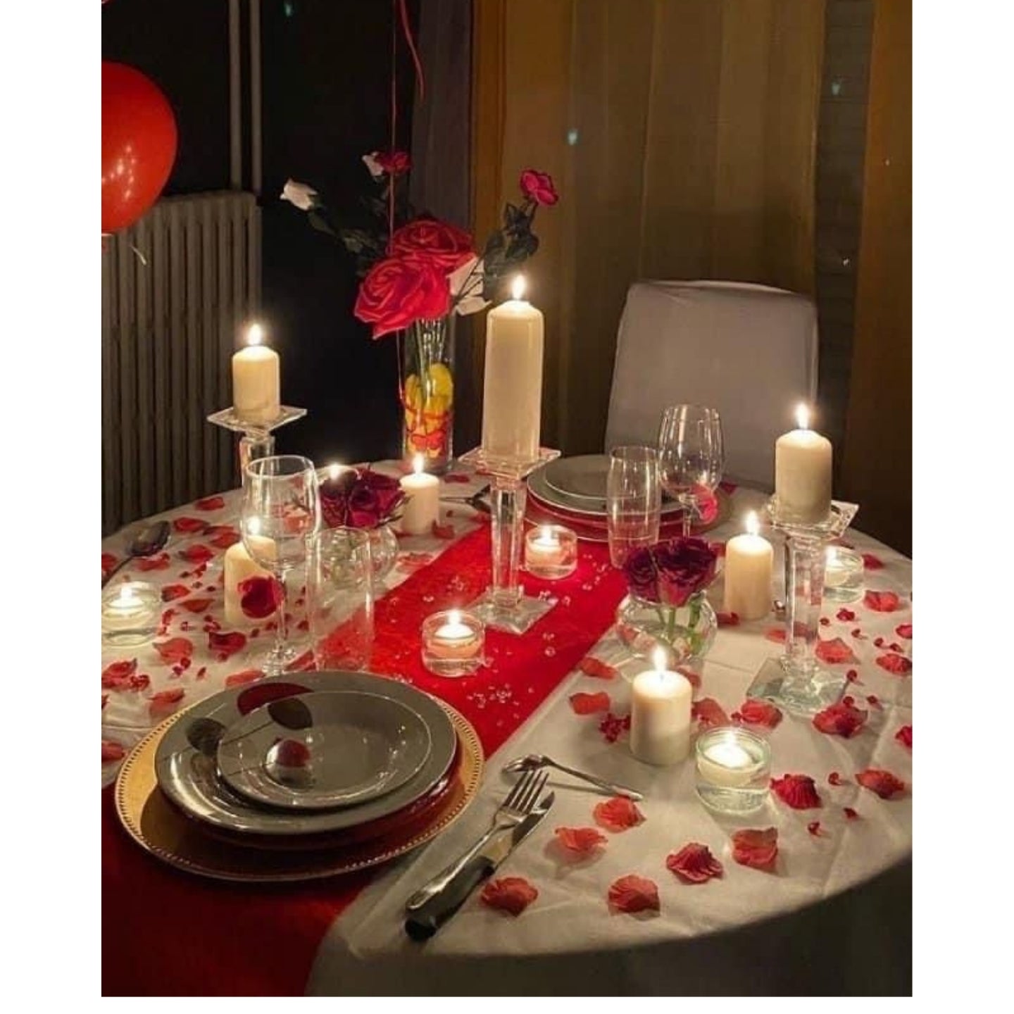 Decorated dinner table with candles, flowers, and red tablecloth.