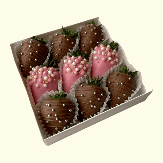 Box of chocolate-covered strawberries with pink and gold decorations on a white background