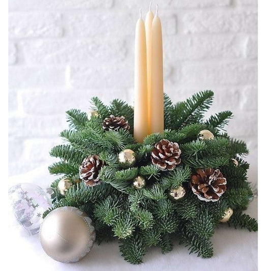 Decorative Christmas arrangement with candles, pinecones, and ornaments on a white background