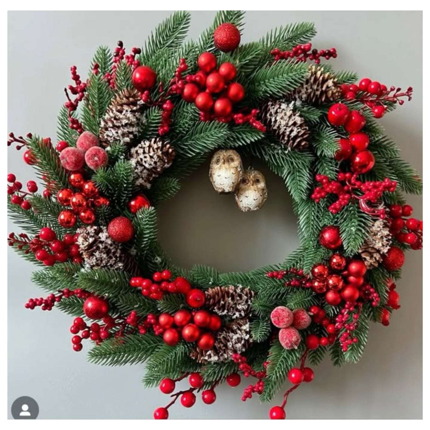 Christmas wreath with red berries and pinecones on a light gray background