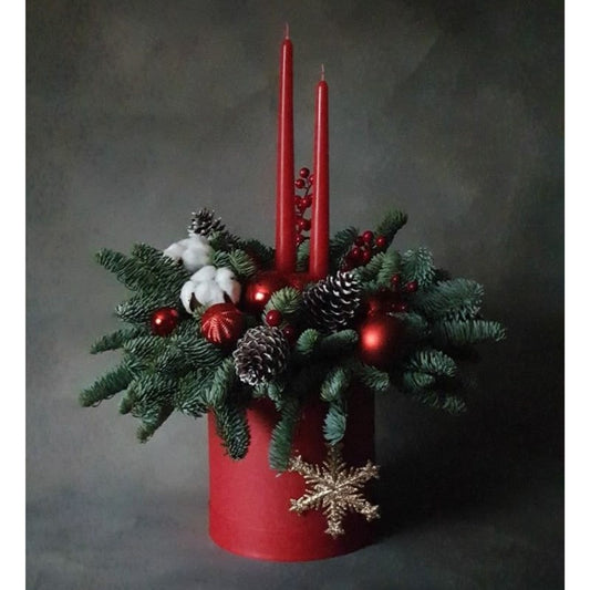 Decorative arrangement with red candles, pine cones, and berries on a dark background