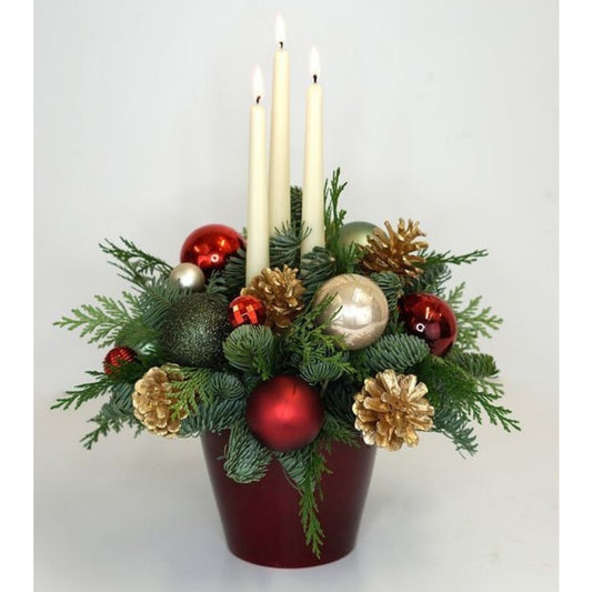Decorative Christmas arrangement with candles, ornaments, and greenery on a white background