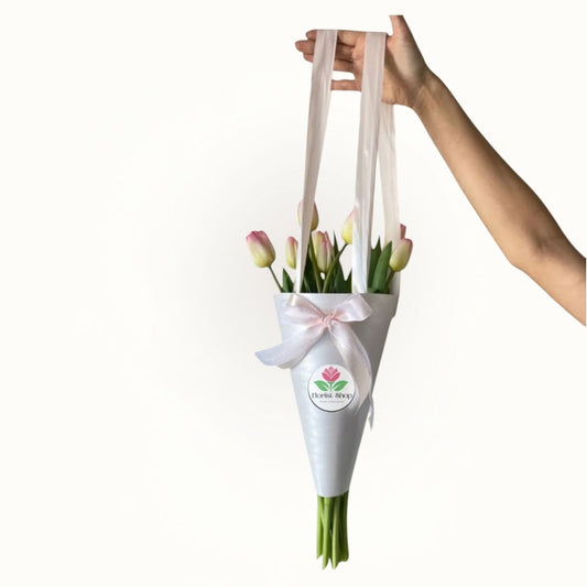 Hand holding a white bag with tulips and a pink bow 
