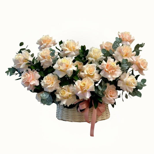 Bouquet of light pink and white flowers in a woven basket on a white background