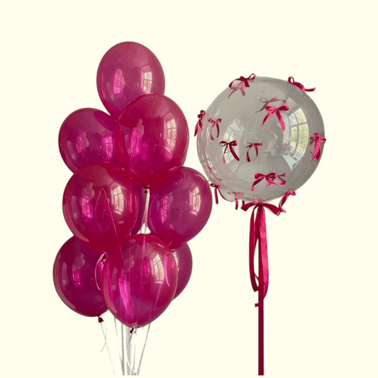 Pink balloons and a clear balloon with red ribbons on a white background