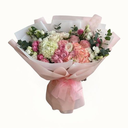 Bouquet of pink and white flowers wrapped in pink paper on a white background