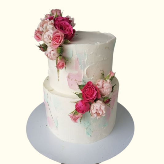 Two-tiered cake decorated with pink and white flowers on a white background