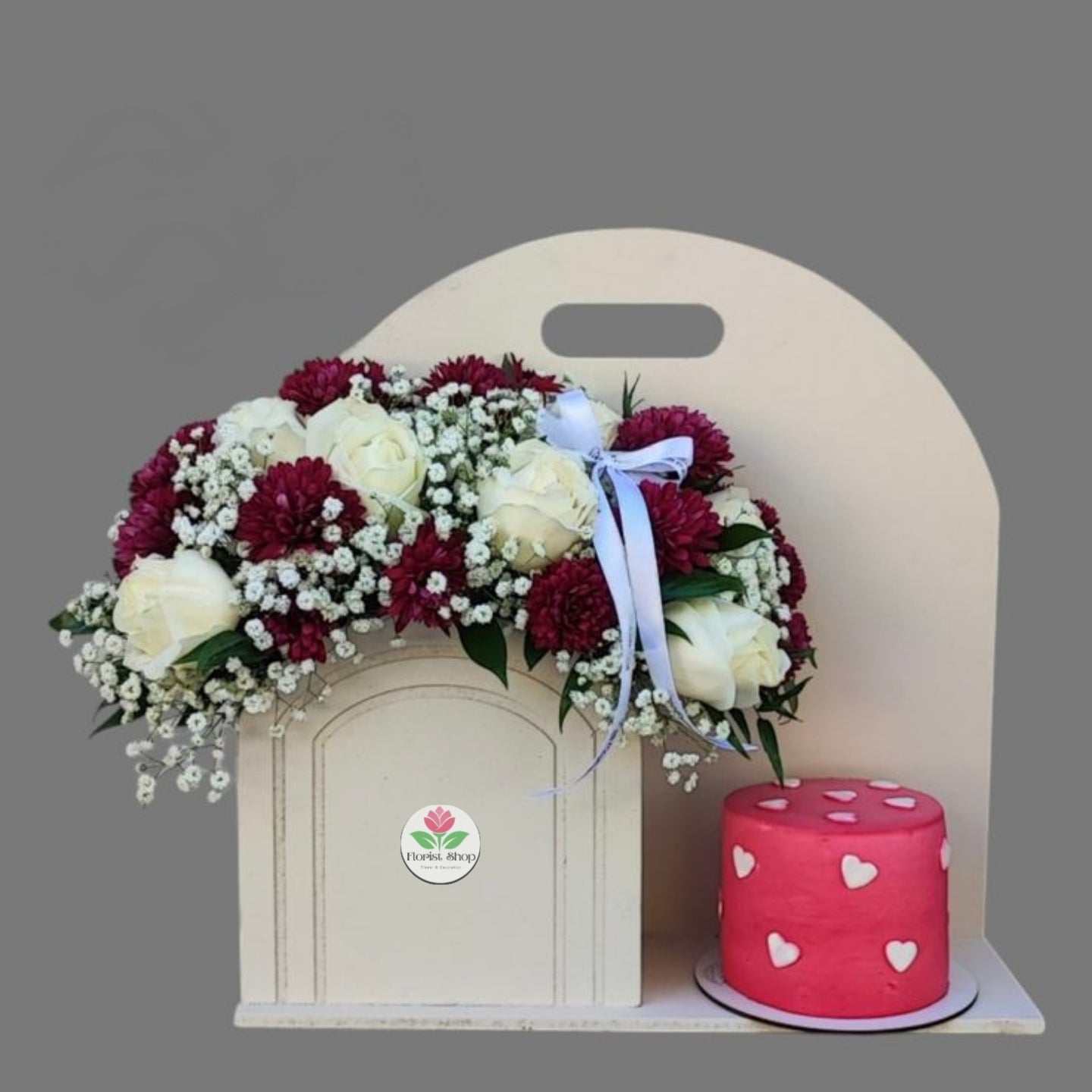 Floral arrangement with a pink cake on a gray background