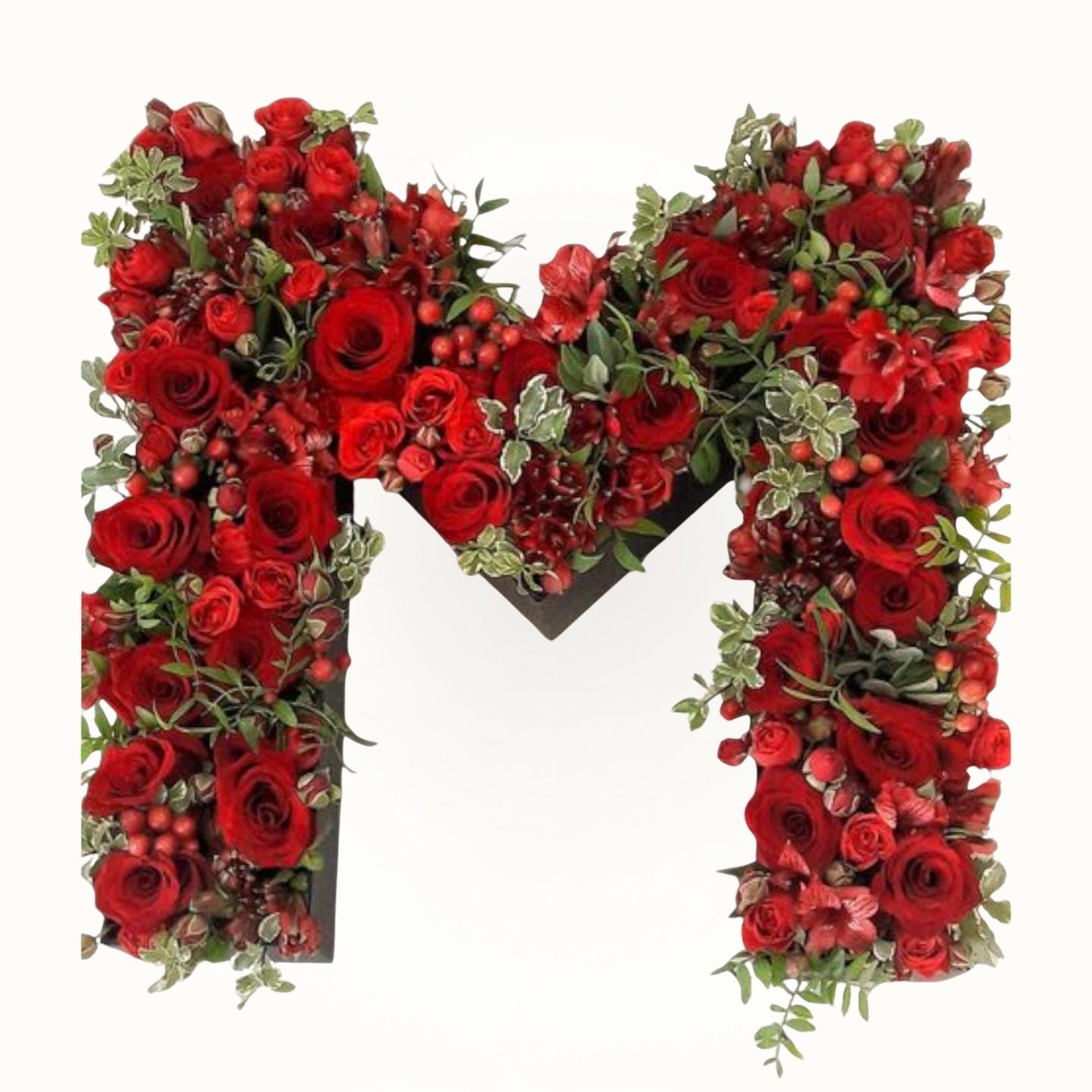Floral arrangement shaped like the letter 'M' with red roses and greenery 