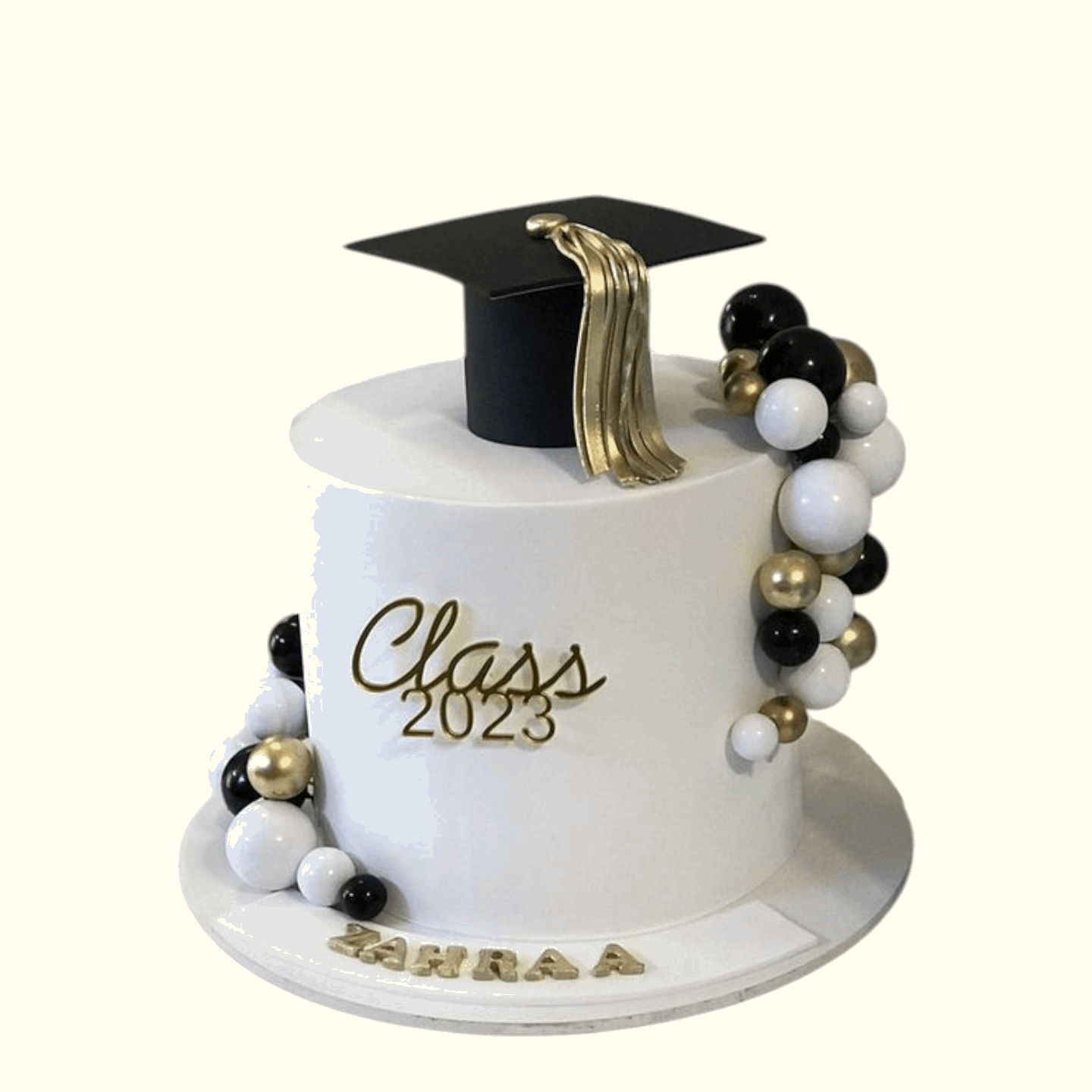 Graduation-themed cake with a black and gold cap, 'Class 2026' text, and decorative beads on a white background.