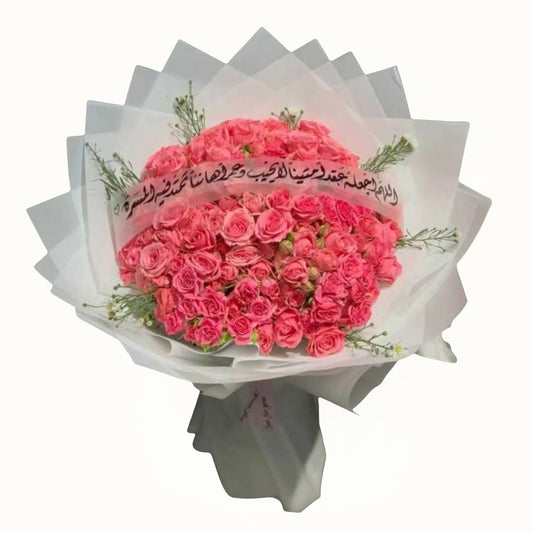 Bouquet of pink flowers wrapped in white paper with Arabic text on a white background
