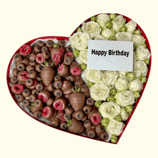 Heart-shaped arrangement of chocolates and flowers with a 'Happy Birthday' card on a white background