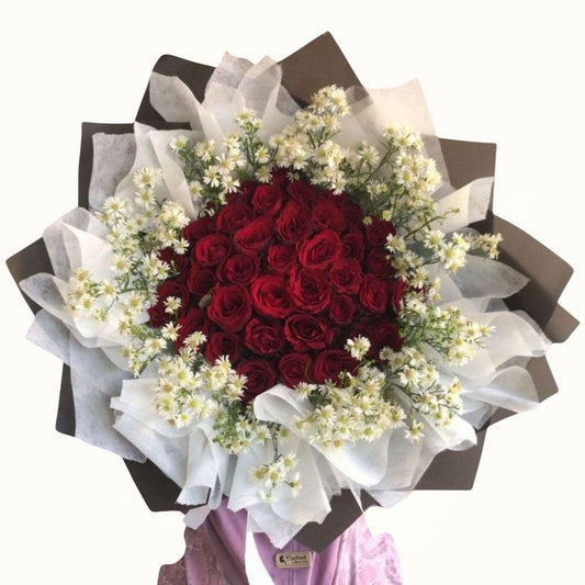 Bouquet of red roses with white flowers wrapped in brown paper on a white background
