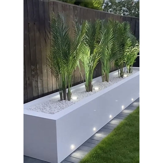 Long white planter with green plants against a wooden fence