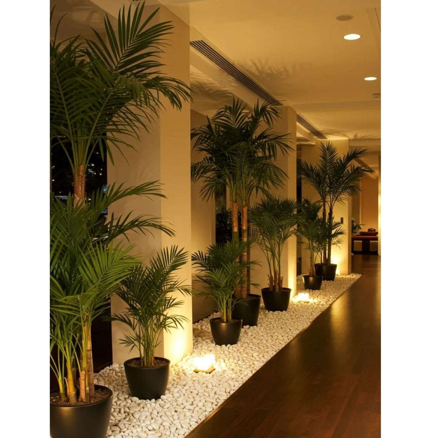 Decorative indoor setting with potted plants and candles on a pebble path.