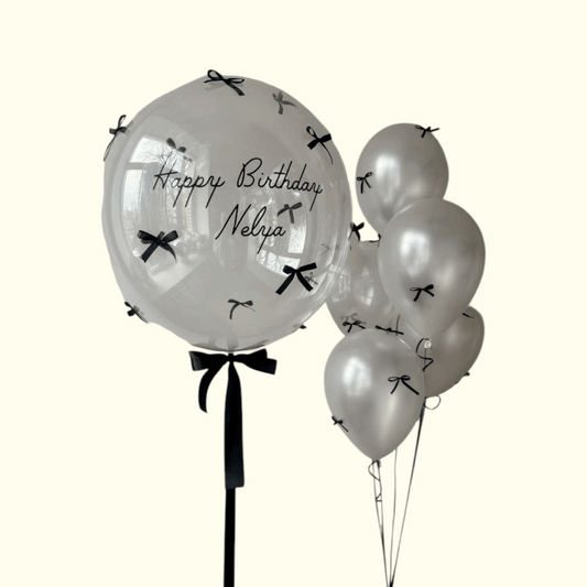 Clear balloons with black bows and text on a white background