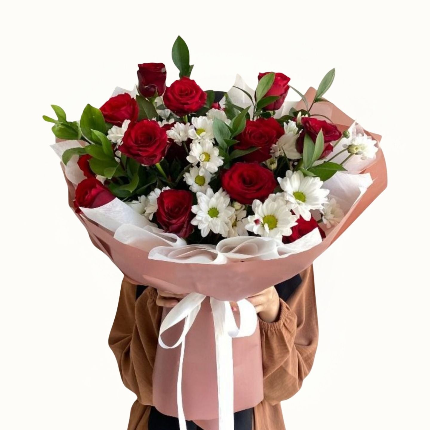 Bouquet of red and white flowers with green leaves held by a person wearing a brown coat.