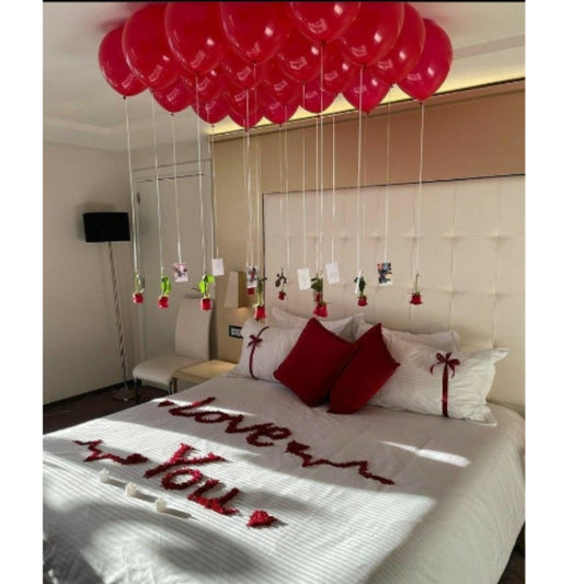 Decorative setup with red balloons and 'I love you' message on a bed.