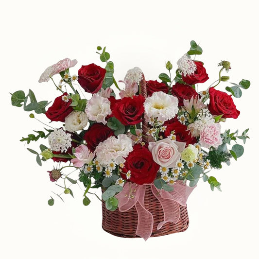 Bouquet of red, white, and pink flowers in a wicker basket on a white background