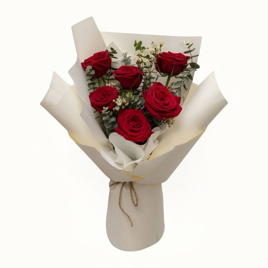 Bouquet of red roses wrapped in white paper on a white background
