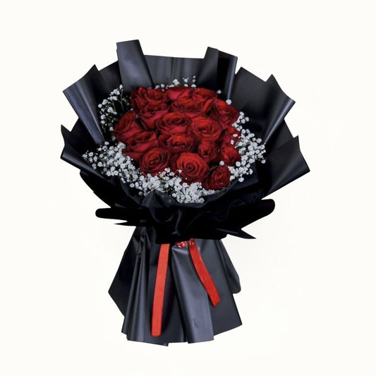 Bouquet of red roses wrapped in black paper with a red ribbon on a white background