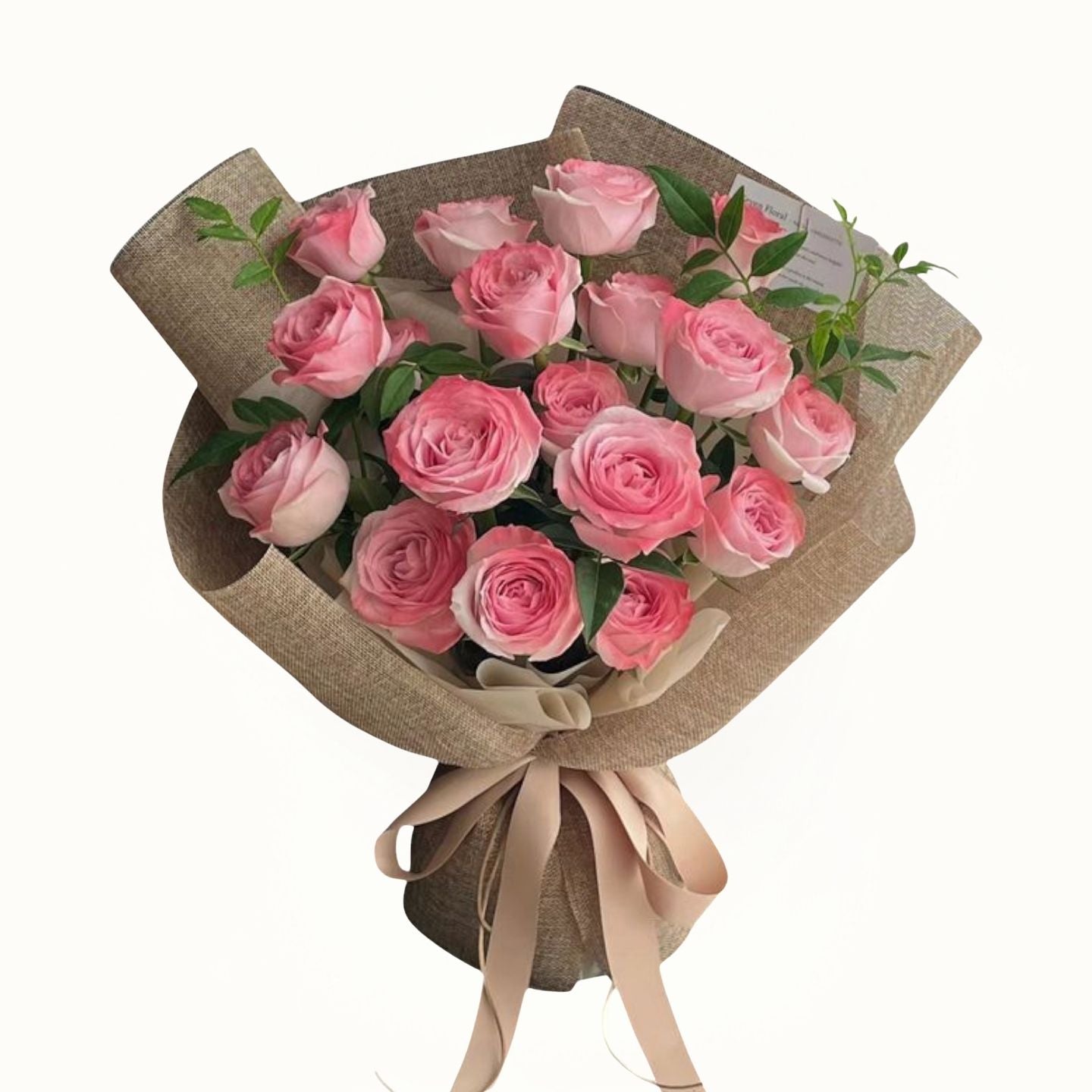 Bouquet of pink roses wrapped in brown paper with a beige ribbon on a white background