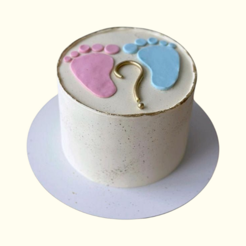 Small round cake with pink and blue footprints and a gold question mark