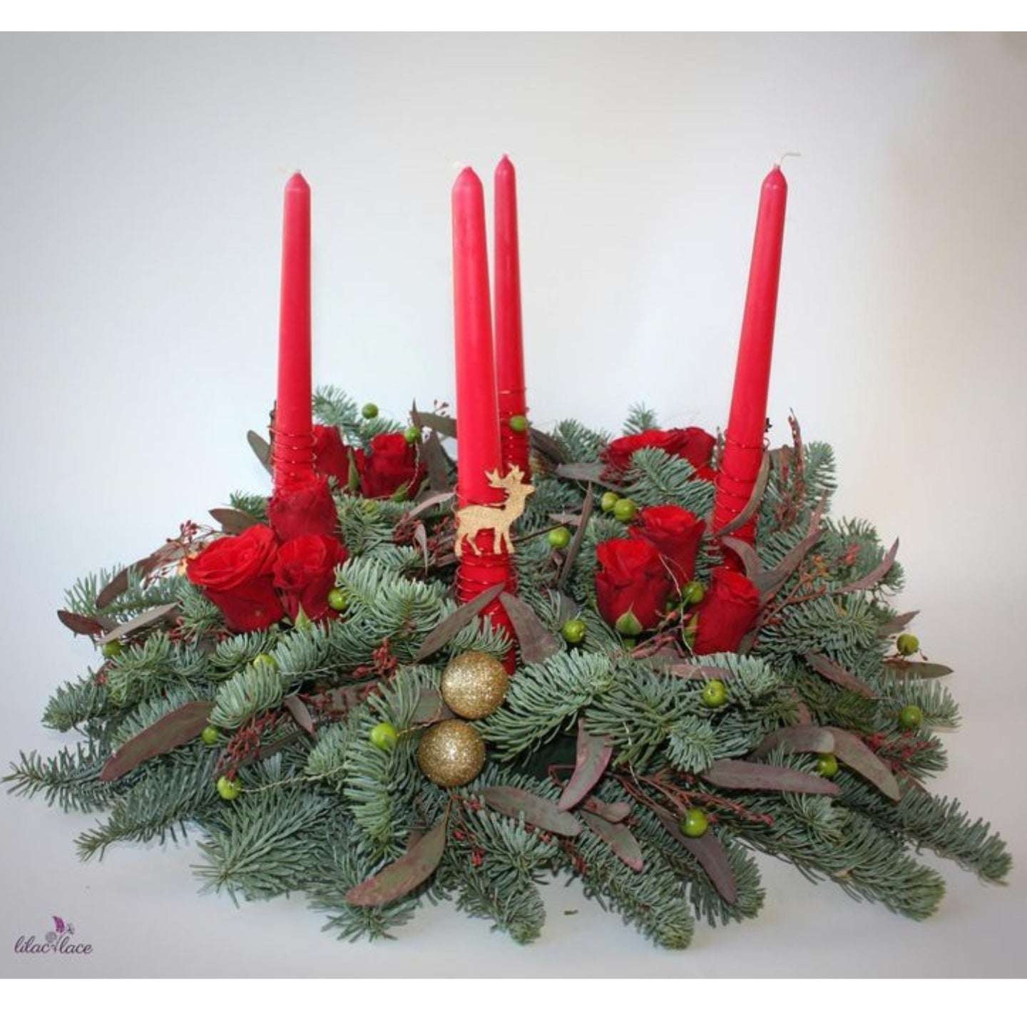 Decorative Advent wreath with red candles, greenery, and gold ornaments on a white background