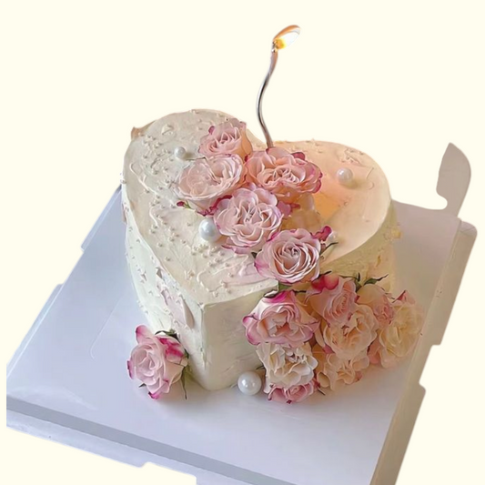 Heart-shaped cake decorated with pink roses and a cherry on top against 