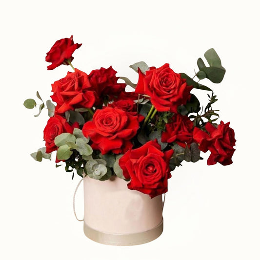 Bouquet of red roses with greenery in a pink box on a white background