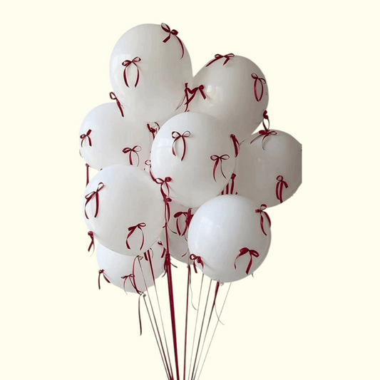 White balloons with red ribbons tied to strings on a white background