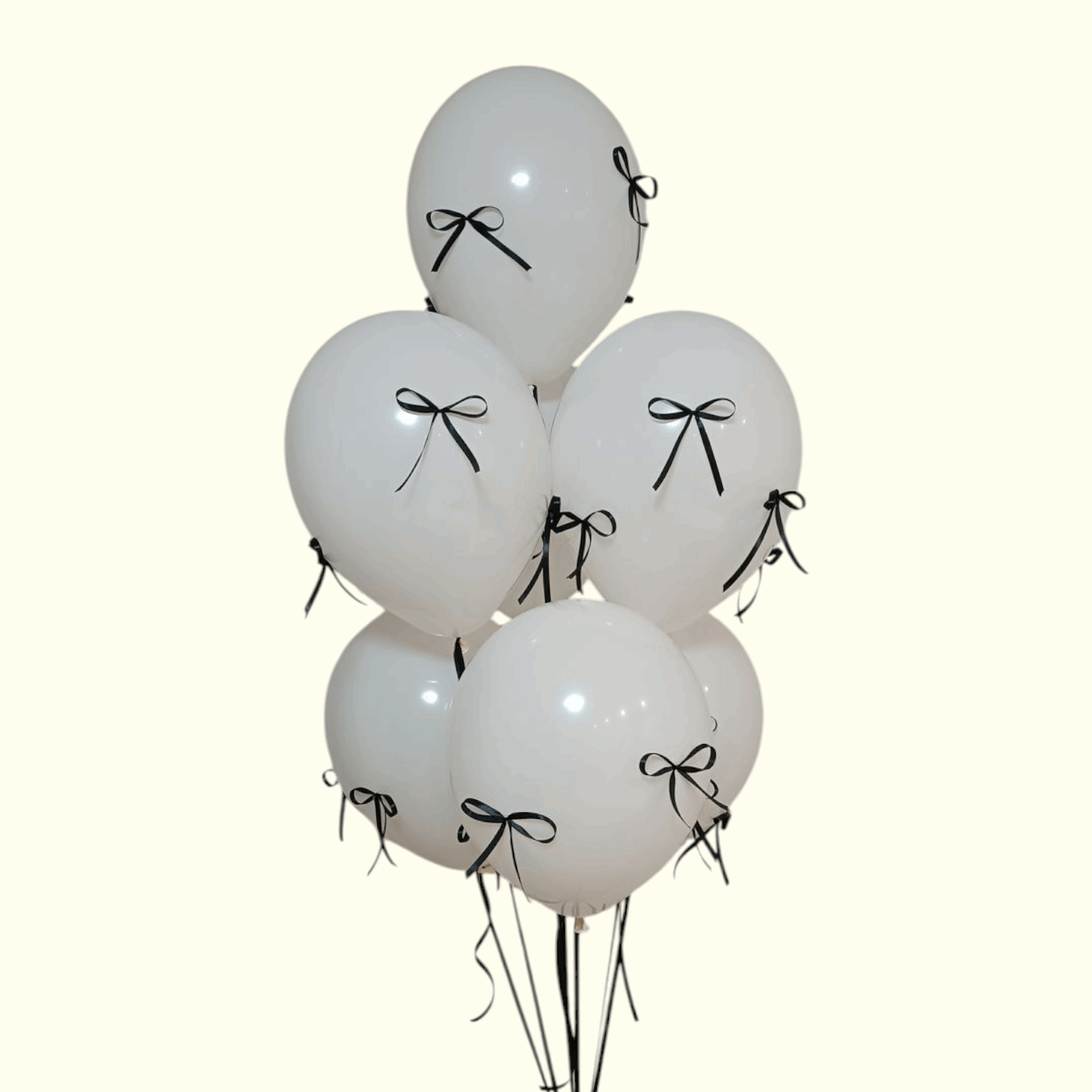 White balloons with black ribbons tied to a stand on a white background