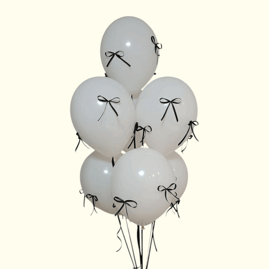 White balloons with black ribbons tied to a stand on a white background