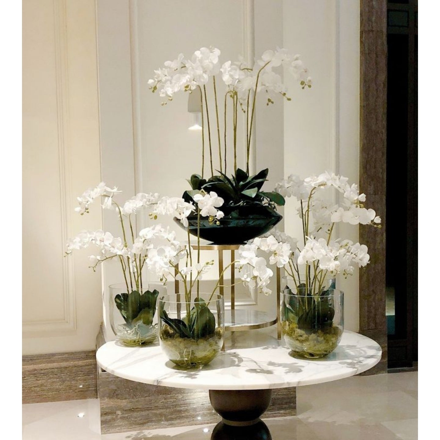 Decorative arrangement of white orchids in glass vases on a marble table.