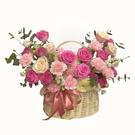 Basket of pink and white flowers with a pink ribbon on a white background